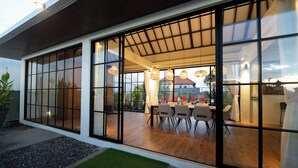 Una casa moderna con amplios ventanales que dan a un comedor con mesa y sillas de madera.