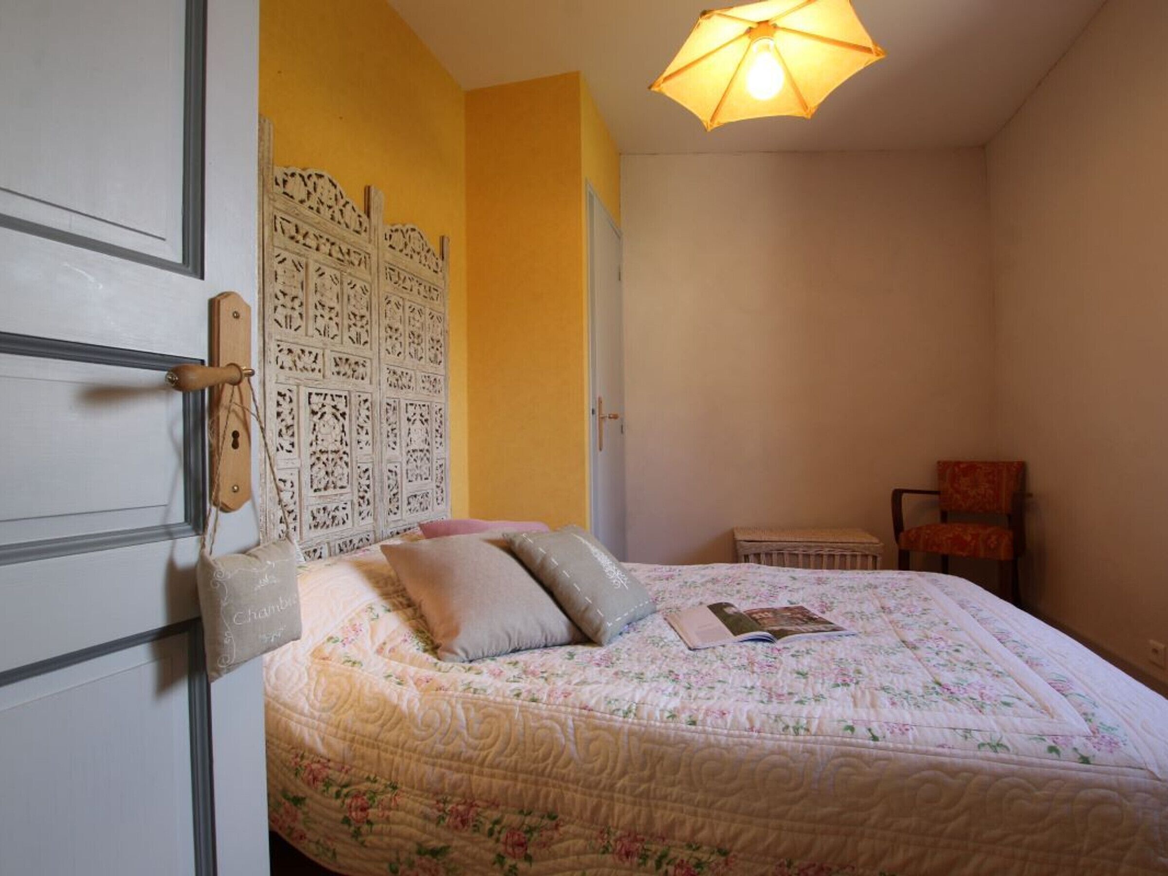 A bedroom with a bed, a chair, and a door with a decorative panel.