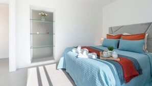Une chambre à coucher moderne avec un lit, une étagère en verre et une table de chevet avec une lampe.