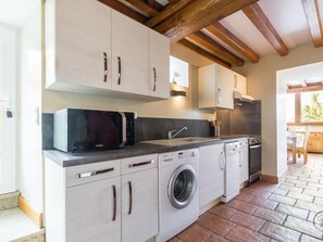 Una cocina moderna con armarios blancos, lavadora integrada, lavavajillas y microondas.