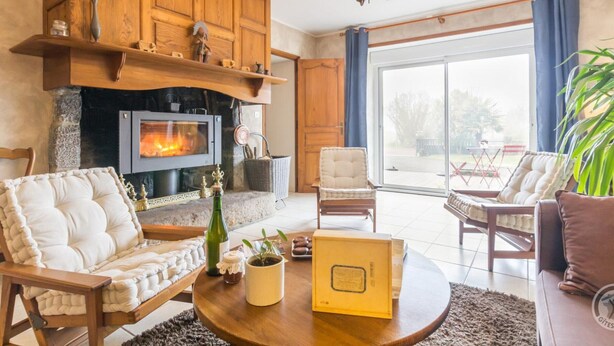 A cozy living room with a fireplace, comfortable seating, and a large window. - Charming Country House with Private Spa, Fireplace, and Family-Friendly Amenities (Bricqueville-la-Blouette)