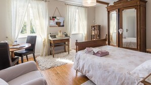 A bedroom with a large bed, a wooden desk, a chair, a mirror, and a wardrobe. - Charming Country House with Private Spa, Fireplace, and Family-Friendly Amenities (Bricqueville-la-Blouette)