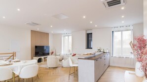 A modern living room with a TV, dining area, and kitchen.
