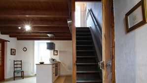 Une cuisine spacieuse dotée d’un îlot central, un coin repas avec une chaise, et un escalier menant à l’étage supérieur.