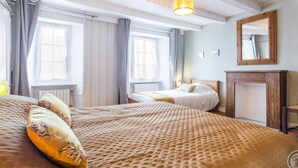 Une chambre d’hôtel avec deux lits, une cheminée et de grandes fenêtres avec des rideaux.