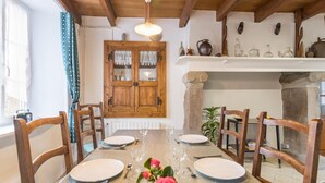 Un coin repas avec une table en bois dressée pour quatre personnes, entourée de chaises en bois. On aperçoit, au fond, un buffet en bois doté de portes en verre.