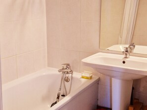 A bathroom with a bathtub, a sink, and a mirror.