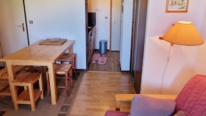 A compact living space with a wooden dining table, benches, a sofa, and a lamp. - Charming 2-room apartment at the foot of the slopes, south/west exposure, Plagne Montalbert (La Plagne Montalbert)