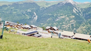 A mountainous village with traditional wooden houses, a ski lift, and a clear view of the surrounding peaks. - Charming 2-room apartment at the foot of the slopes, south/west exposure, Plagne Montalbert (La Plagne Montalbert)