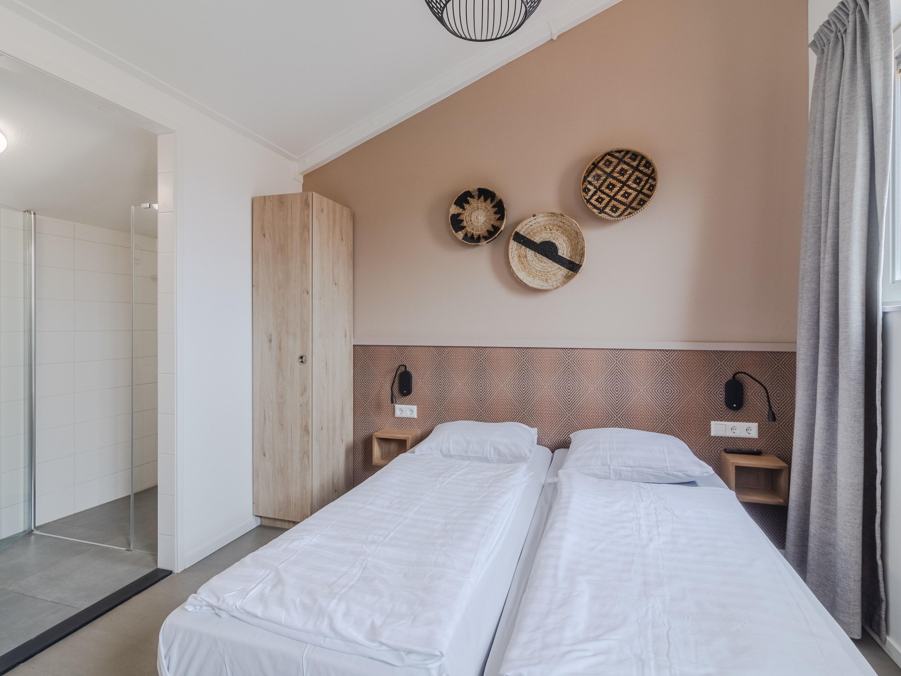 A hotel room with a bed, bedside tables, a wardrobe, and wall decor.