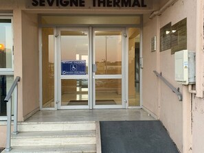 The entrance to Sevigne Thermal with a wheelchair-accessible ramp and a sign indicating access to the parking area.
