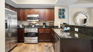 Una cocina moderna con electrodomésticos de acero inoxidable, armarios de madera oscura y encimera de granito.