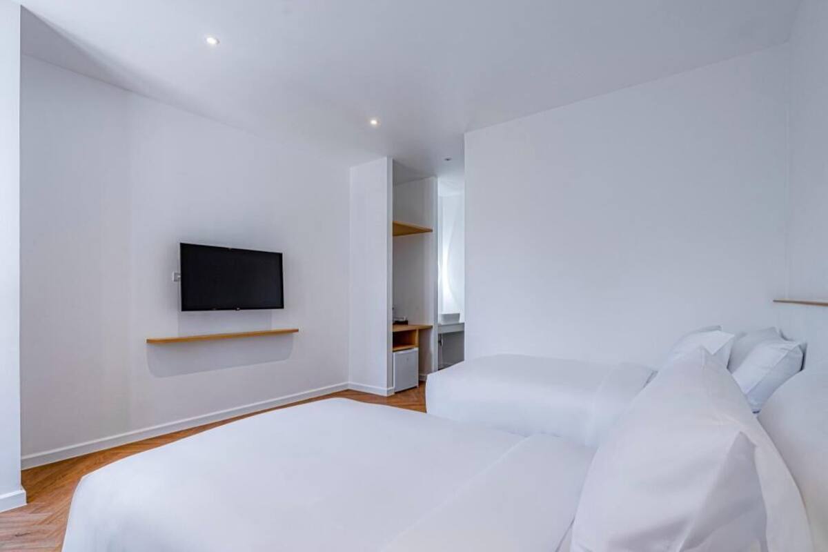 A modern bedroom with a bed, a TV mounted on the wall, and a closet with shelves.