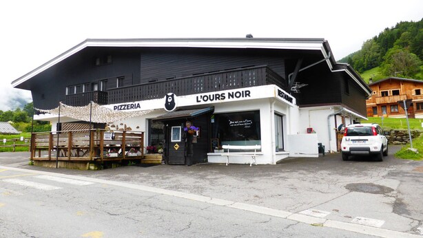 Un edificio con un letrero que dice "PIZZERIA" y "L'OURS NOIR RESTAURANT".