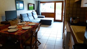 Un comedor con una mesa dispuesta para cuatro personas, un sofá y una televisión.