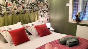 A hotel room with a bed, pillows, a nightstand, a lamp, and a window with a curtain. - Charming Family-Friendly Cottage, Pet Welcome, Garden, Near Blois & Loire Castles (Valencisse-Chambon-sur-Cisse)