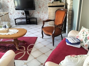 A living room with a sofa, a chair, a table, and a television.