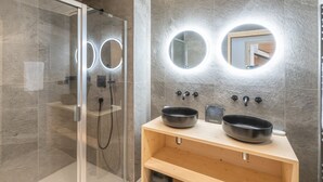 A modern bathroom with a glass-enclosed shower, two round mirrors with underglow lighting, and two black vessel sinks on a wooden vanity. - 125m² Ski-In Duplex with PARKING, 4 Bedrooms (Huez)