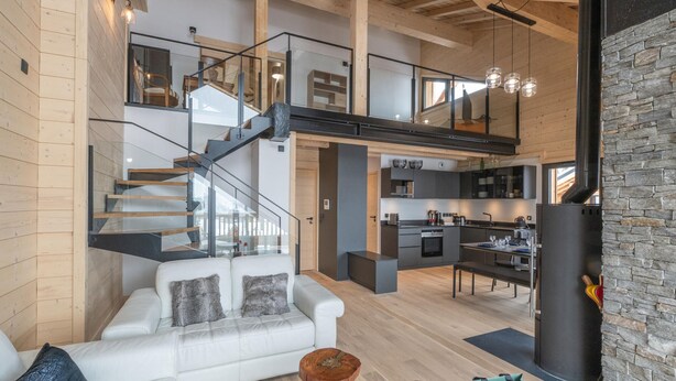 A modern interior with a white sofa, a wooden coffee table, and a stone fireplace. - 125m² Ski-In Duplex with PARKING, 4 Bedrooms (Huez)