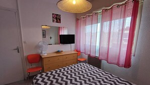Ein Schlafzimmer mit Bett, Kommode, Spiegel und Fernseher.