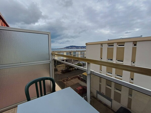 Un balcón con vistas a un paisaje urbano, que incluye edificios y una colina distante.