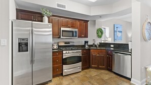 A modern kitchen with stainless steel appliances, wooden cabinets, and a tiled floor. - Spectacular 8th Floor Serenity: Oceanfront Views (North Myrtle Beach)