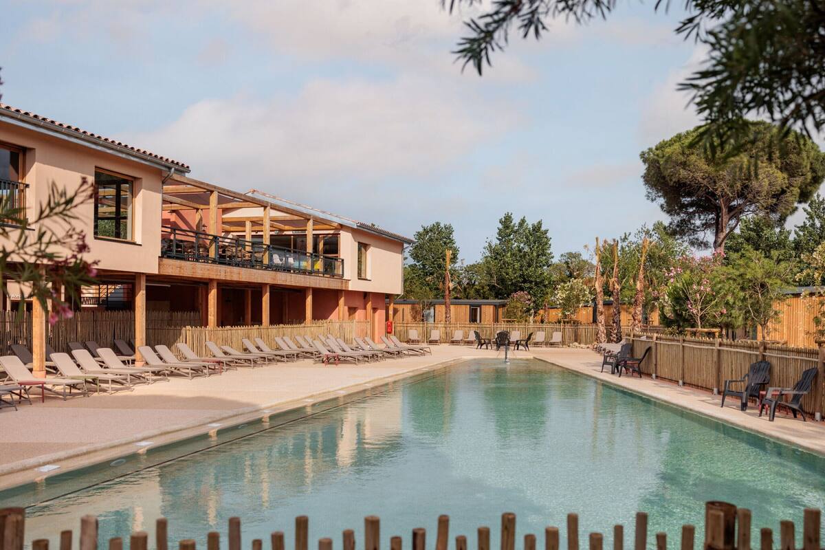 A pool area with lounge chairs and a building with multiple balconies.