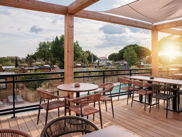 A wooden deck with outdoor seating, a pool, and a view of the surrounding area. - Sunny Chalet Close to Sea (Agde)