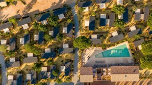 Luchtbeeld van een resort met verschillende bungalows, een centraal zwembad en omliggend groen.