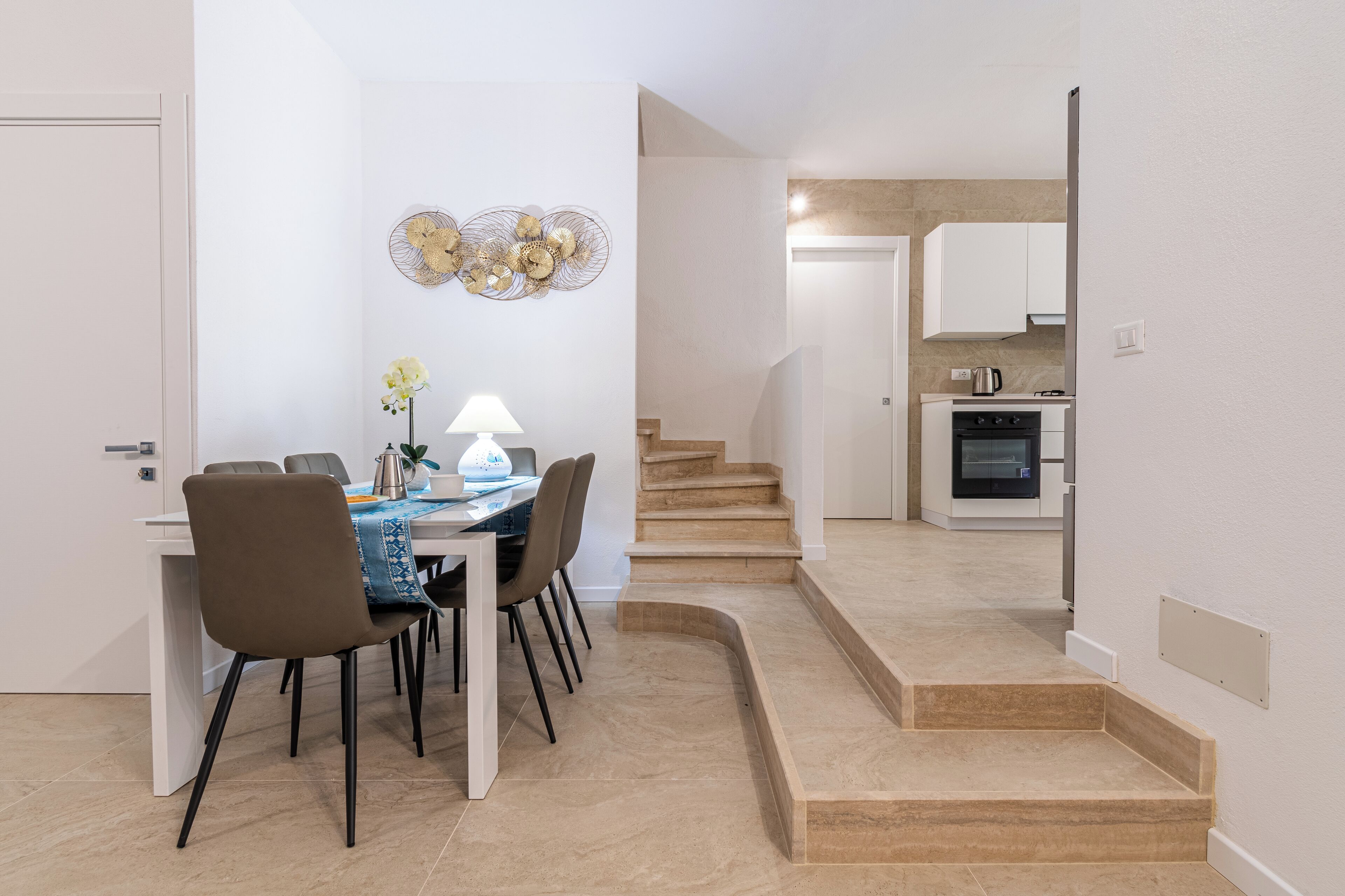 A modern kitchen with white cabinets, a stove, and a coffee maker.