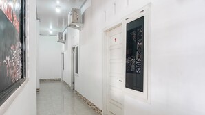 Un corridoio pulito e ben illuminato, con pavimento piastrellato, una porta bianca con un numero e un condizionatore d'aria a muro.