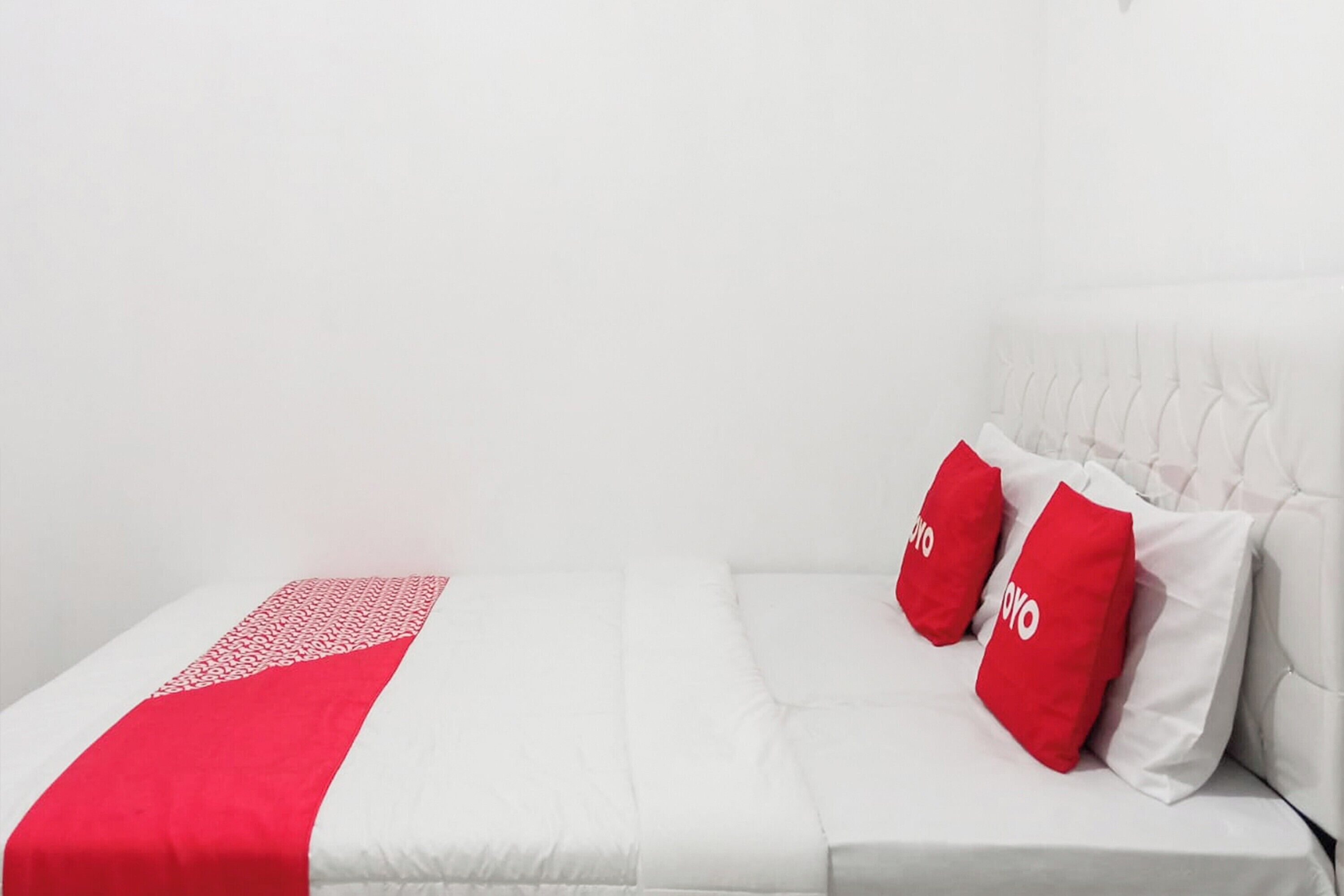 A white bed with red pillows and a red and white blanket.