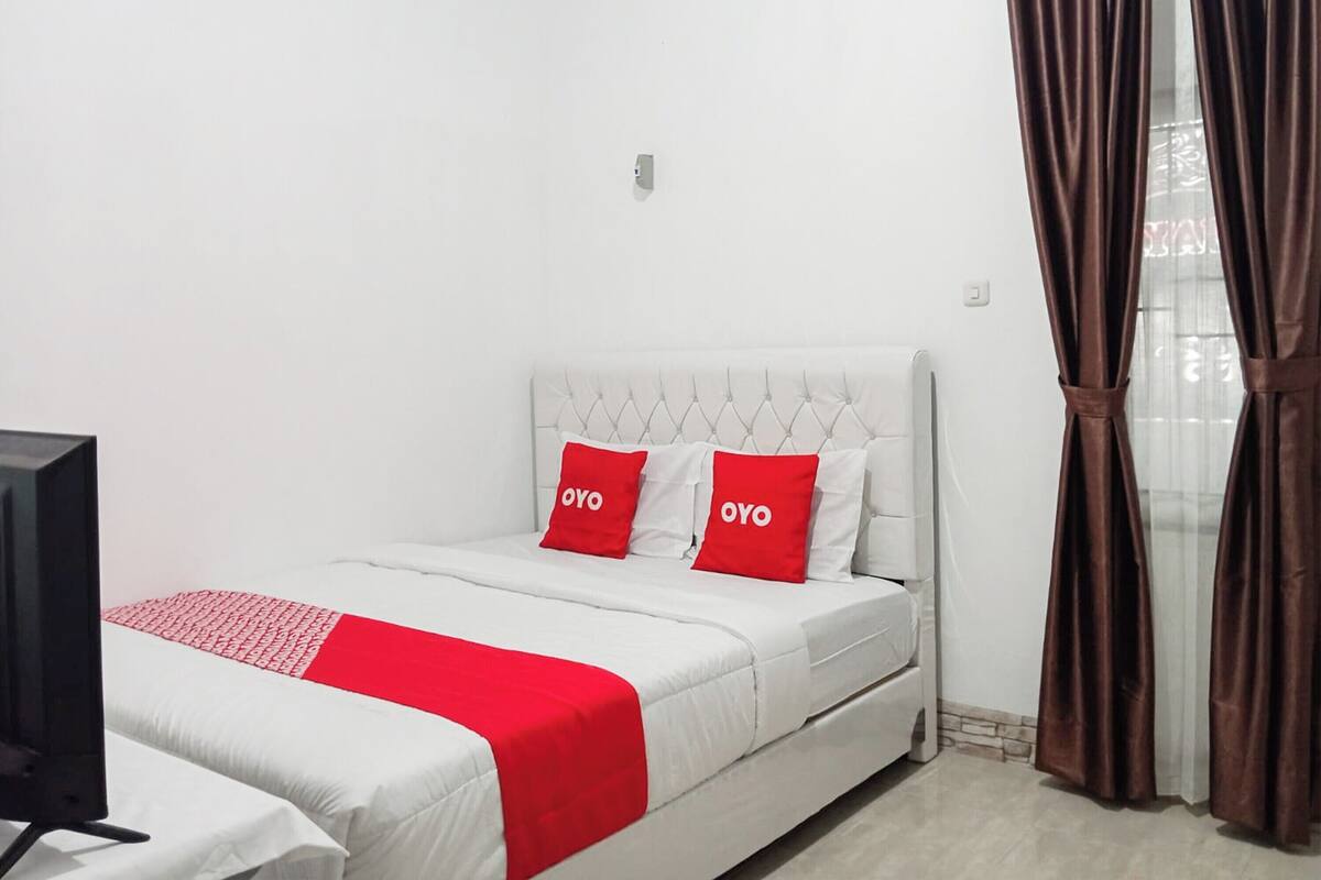 A hotel room with a bed, a television, and curtains.