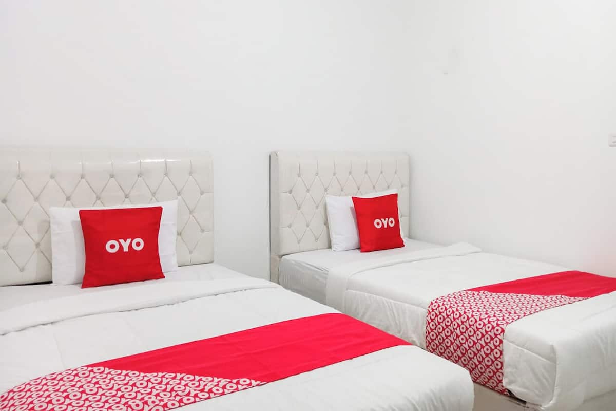 Two beds with white headboards and red pillows, each with the word "OYO" on them.