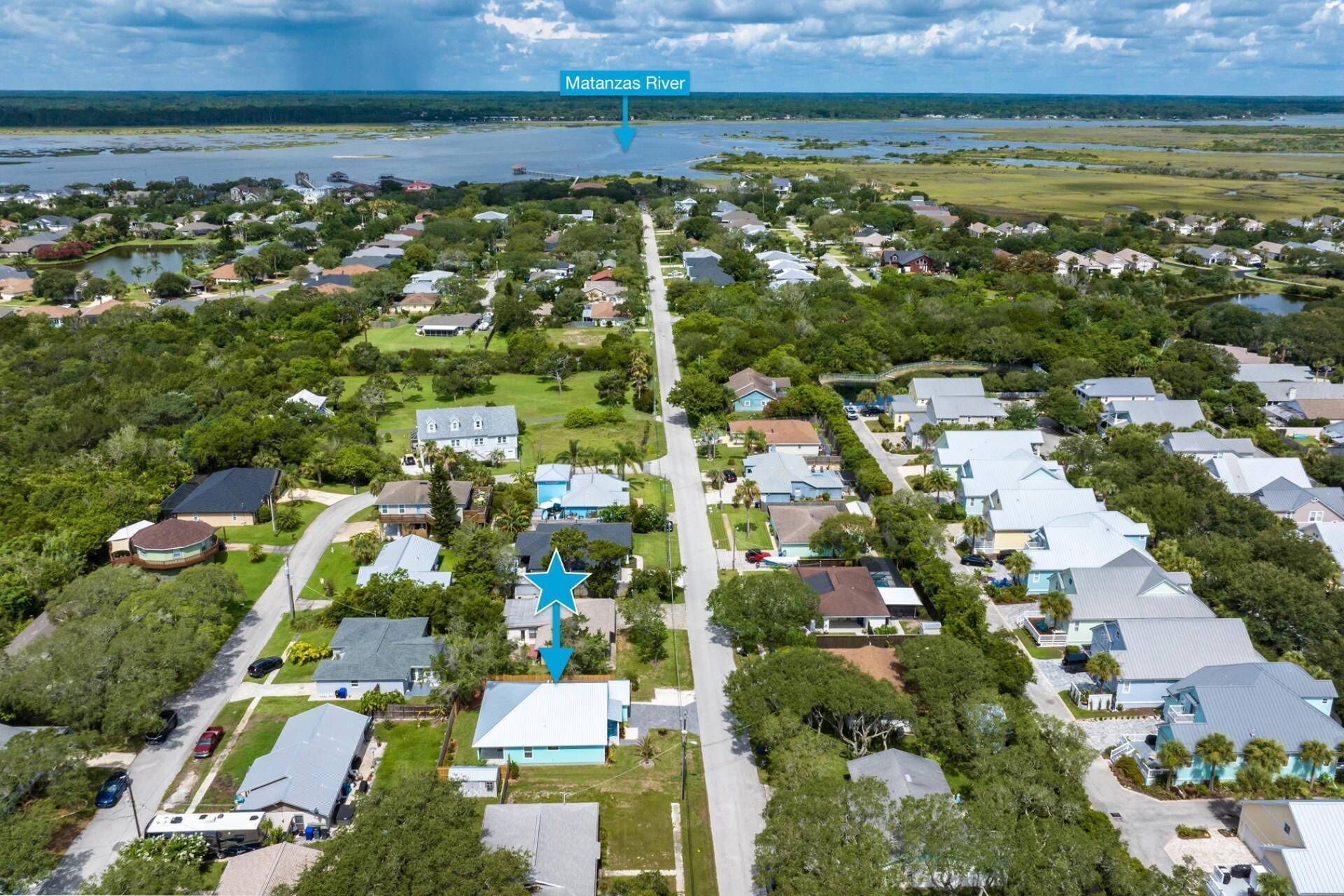 An aerial view of a residential area with houses, a star-shaped building, and the Matanzas River in the background.