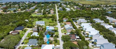 An aerial view of a residential area with houses, a star-shaped building, and the Matanzas River in the background.