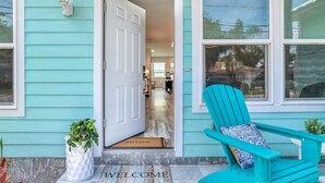 A turquoise house with a white door, a blue chair, and a welcome mat. - Aqua Palms Cottage (St. Augustine)