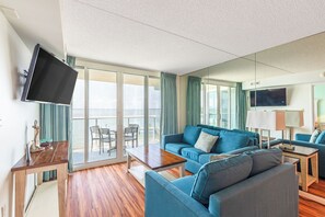 A modern living room with a blue sofa, a wooden coffee table, and a flat-screen TV mounted on the wall.