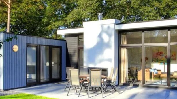 A modern house with a patio, a dining area, and a large glass door leading inside. - Veluwemeer Chalet Park Retreat (Hulshorst)