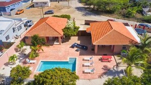 A residential property with two houses, a swimming pool, and a patio area with lounge chairs. - Ideal Home for Larger Family with Pool in Noord (Noord)