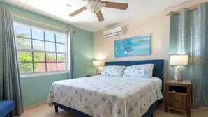 A bedroom with a bed, a ceiling fan, a window, and a painting on the wall. - Ideal Home for Larger Family with Pool in Noord (Noord)
