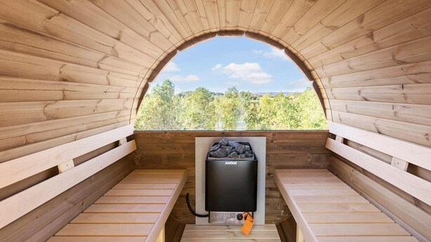Sauna, josta avautuu näkymä puita kohti holvikaaren muotoisen aukon kautta.