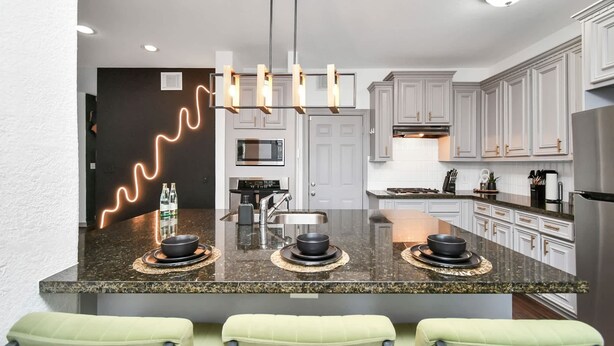 A modern kitchen with granite countertops, stainless steel appliances, and a central island with seating.