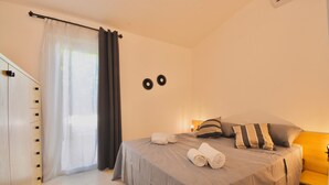 Camera da letto con un letto, un comodino, una lampada e una finestra con tende.