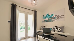 Una camera moderna con un tavolo in vetro, sedie bianche, un portatile e un quadro con dei delfini.