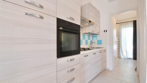 Una cucina moderna con forno nero, maniglie in acciaio inossidabile e mobili dai colori chiari.