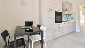 Una cucina moderna con mobili bianchi, un forno nero e un tavolo da pranzo con due sedie.