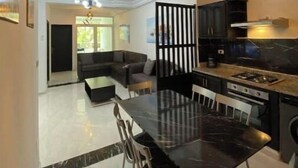 Cozinha moderna com área de refeições, apresentando uma mesa e cadeiras de mármore preto, uma ilha de cozinha e um lustre contemporâneo.
