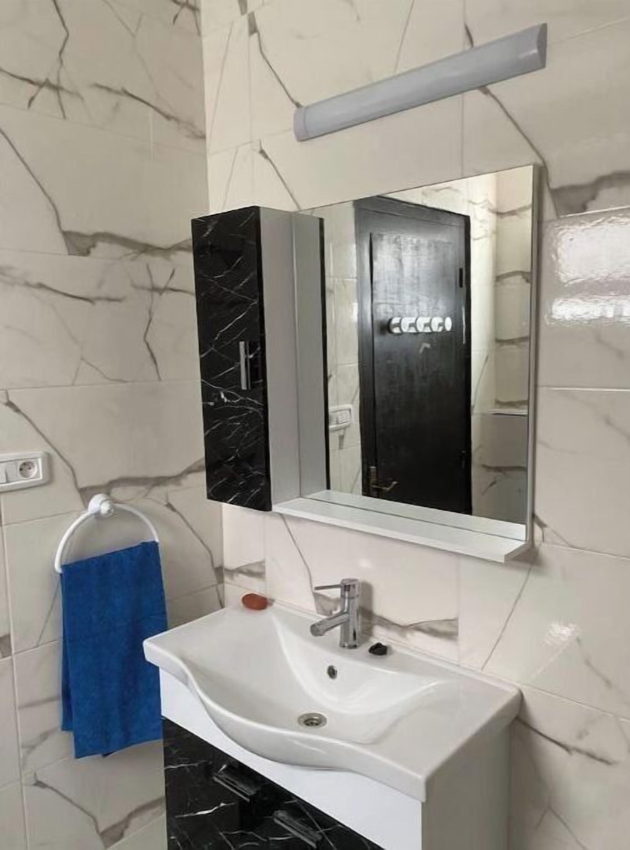 A bathroom with a white sink, a mirror, and a towel rack with a blue towel.