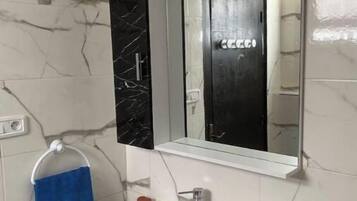 A bathroom with a white sink, a mirror, and a towel rack with a blue towel.